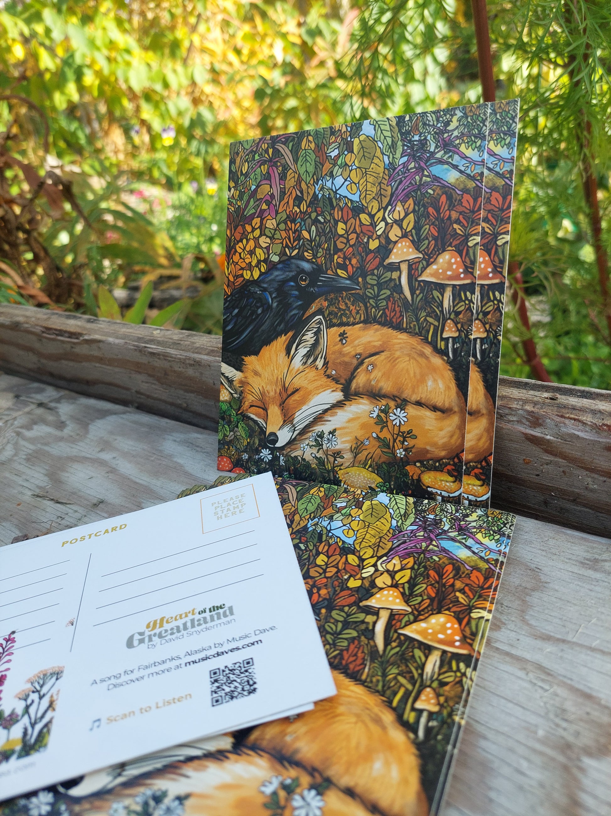 Postcard with a fox and crow design on a wooden surface with a natural background