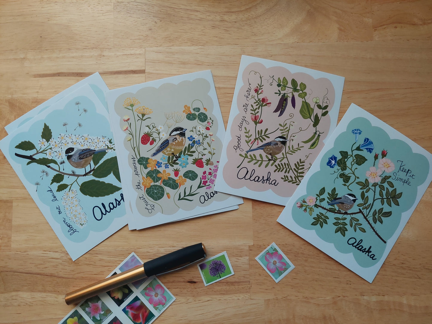 Set of decorative cards with floral and bird designs on a wooden surface.